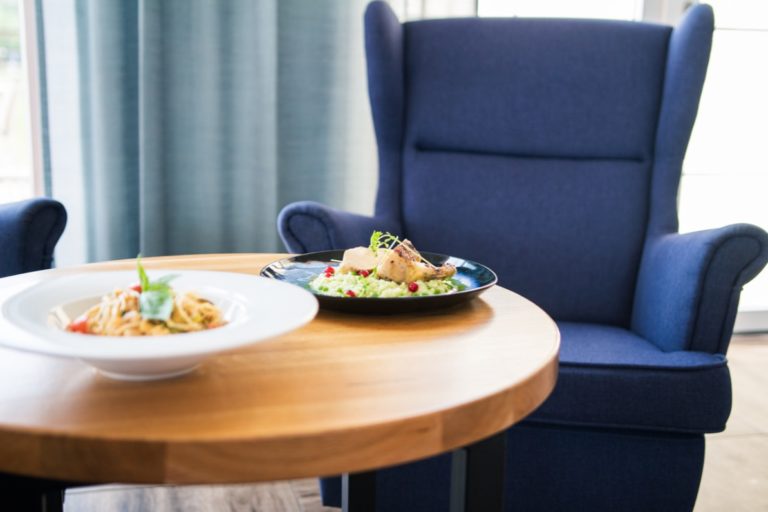 Angerichtetes Essen am Tisch mit Stuhl daneben